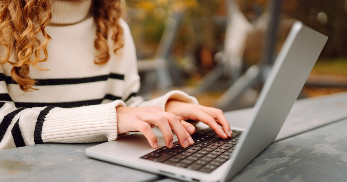 woman typing on a laptop outside