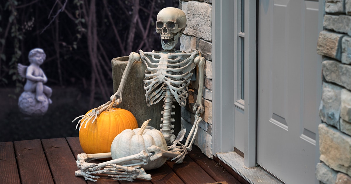 A skeleton and pumpkin Halloween decorations sit outside a chiropractic practice's door.